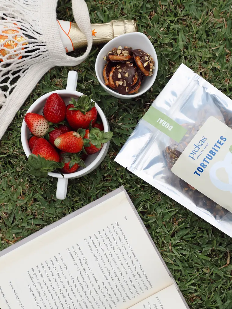 Picnic en el pasto con fresas, un libro y una bolsa de tortubites